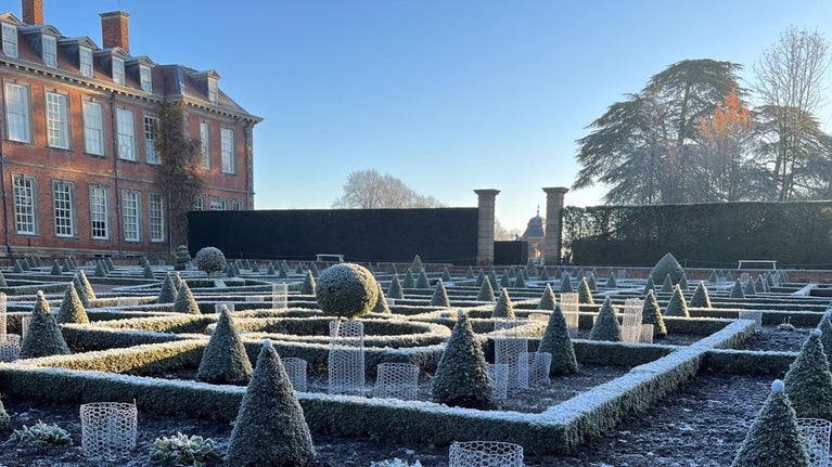 The parterre garden at Hanbury Hall covered in frost on a sunny day with the Hall behind